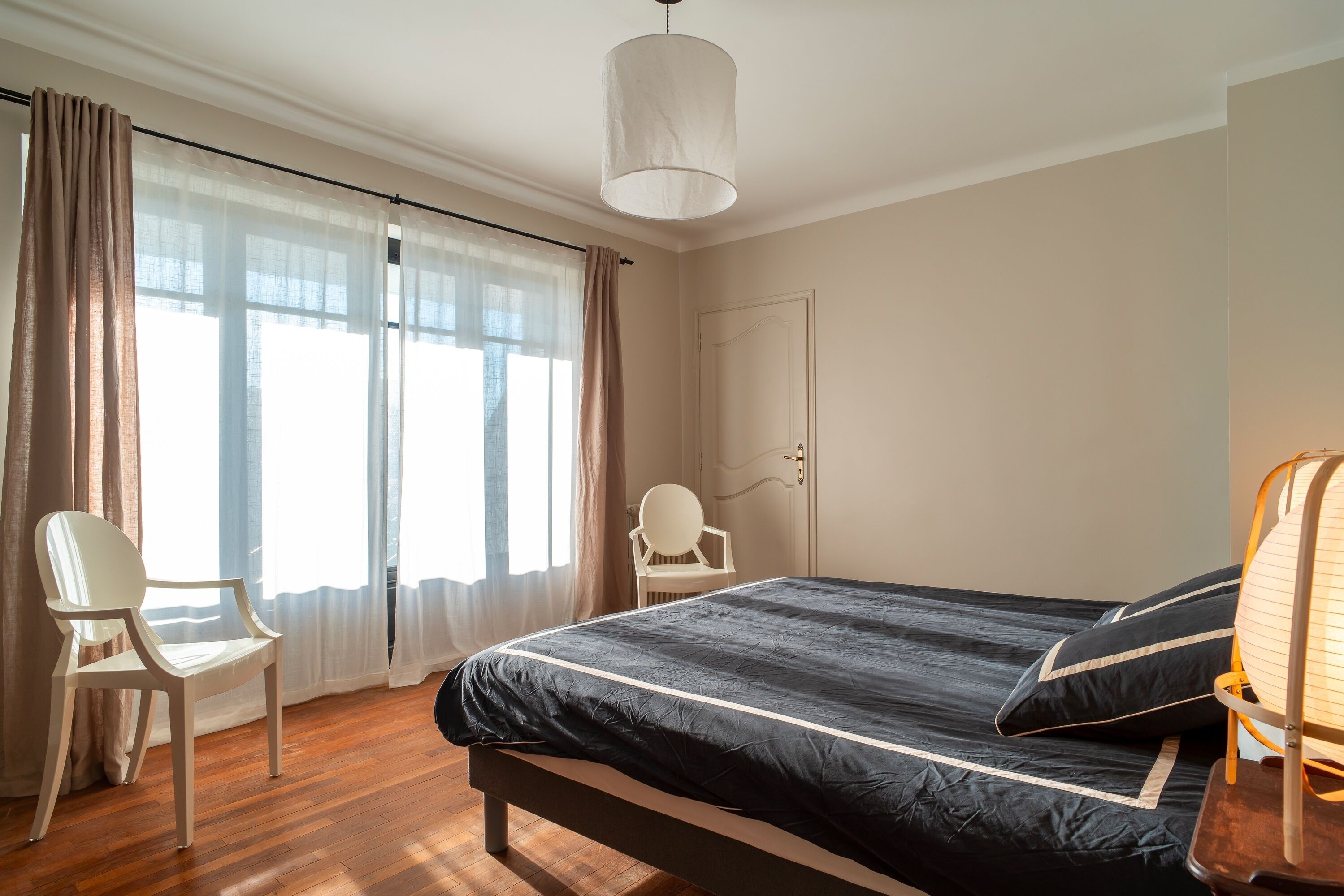 A bedroom with a bed, a chair, a desk, and a door.