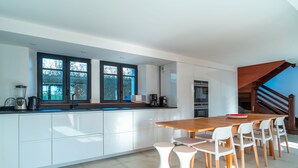 Una cocina moderna con armarios blancos, una mesa de comedor de madera y taburetes blancos.