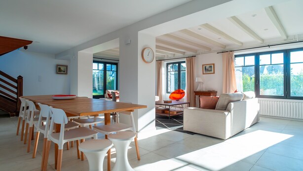 Amplia sala de estar con una mesa de comedor, sillas, un sofá y una ventana con cortinas.