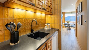 Une cuisine avec des meubles en bois, un évier noir et un dosseret carrelé.