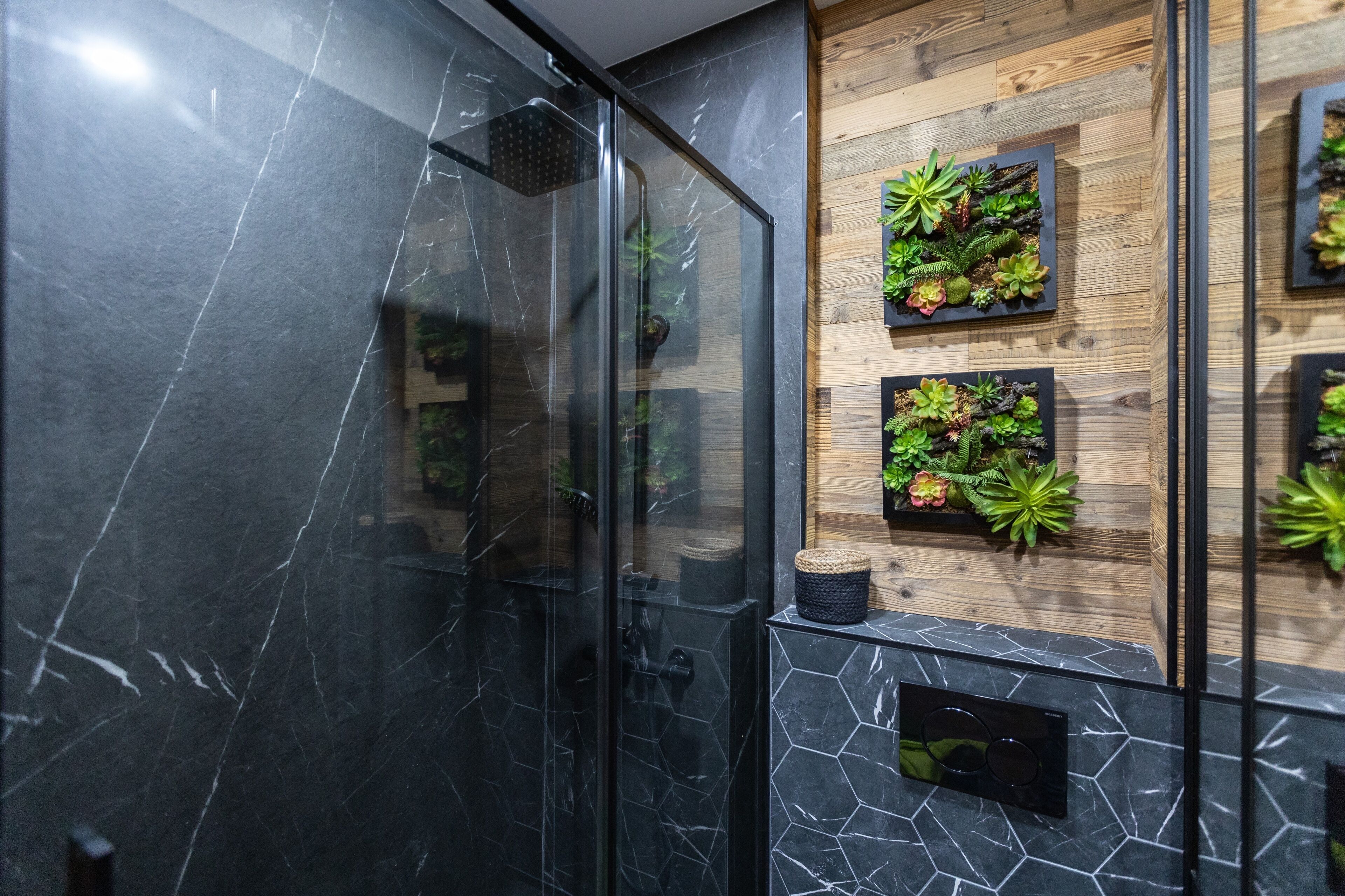 Ein modernes Badezimmer mit einer gläsernen Dusche, einer Holzwand mit Sukkulentenpflanzgefäßen und einem Marmorboden.