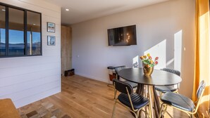 Un espace repas moderne avec une table ronde, des chaises noires et un vase de fleurs.