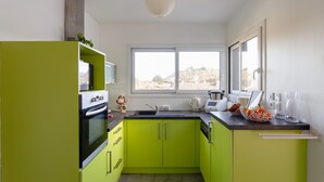 A kitchen with green cabinets, a white stove, and a window with a view of a hill.