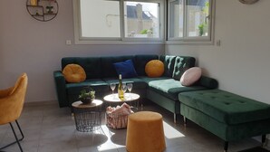 A living room with a green sofa, two round coffee tables, and a single chair.