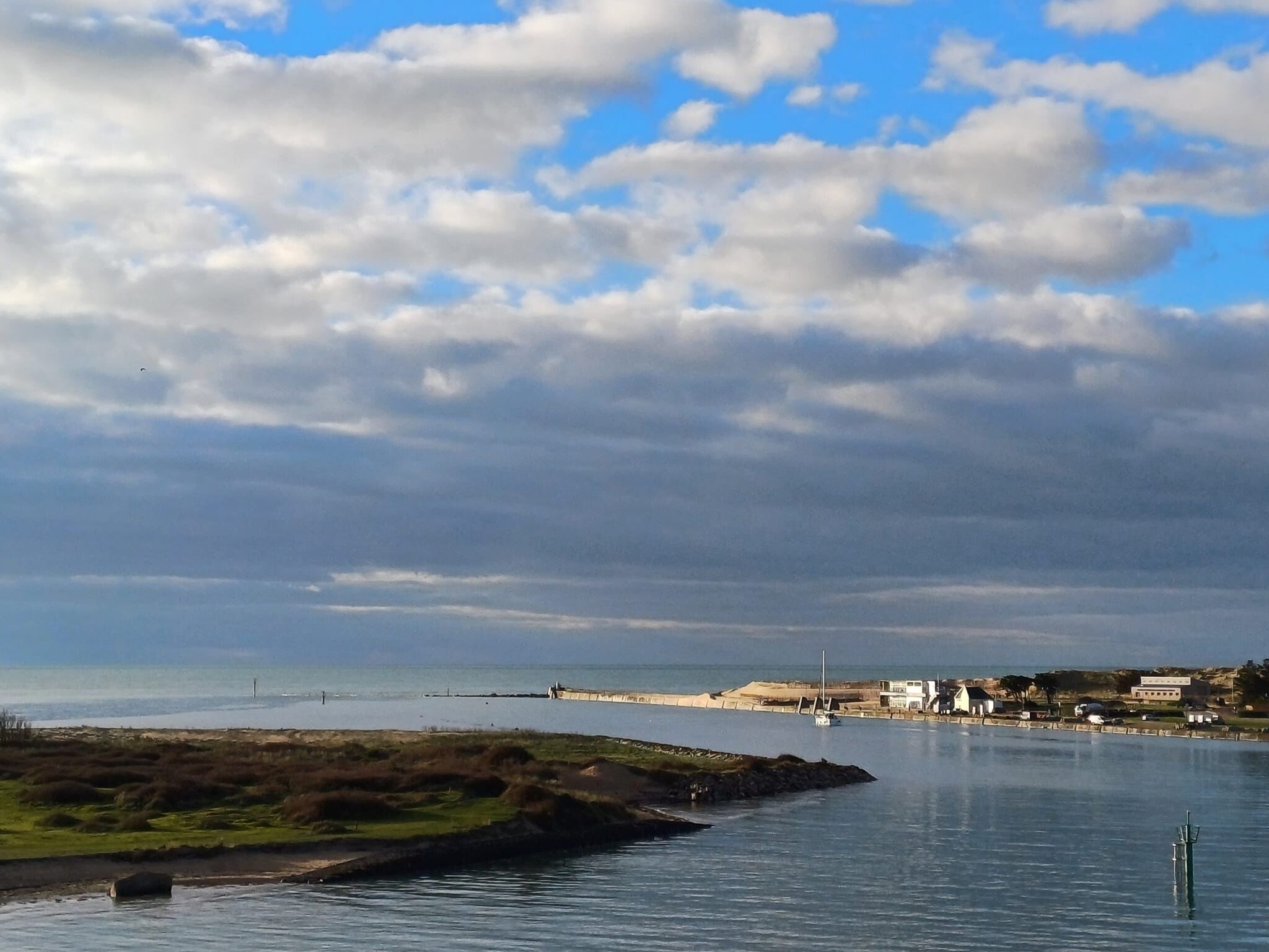 A coastal landscape with a clear sky, a body of water, and a distant shoreline with buildings.