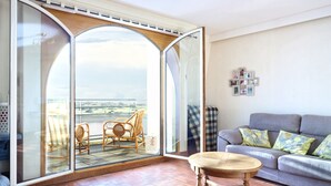 Una sala de estar con un sofá, una mesa y vistas al exterior a través de un amplio ventanal.