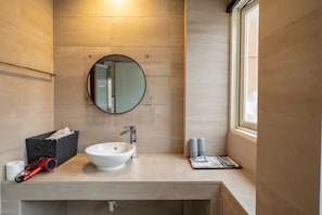 A bathroom with a round mirror, white sink, and a window. - Mutaixu-HotSpring (Jiaoxi)