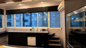 Et moderne køkken med et stort vindue, indbyggede hårde hvidevarer og en trappe til en etage ovenover.