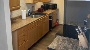Una cocina con armarios de madera, microondas, fregadero y estufa.