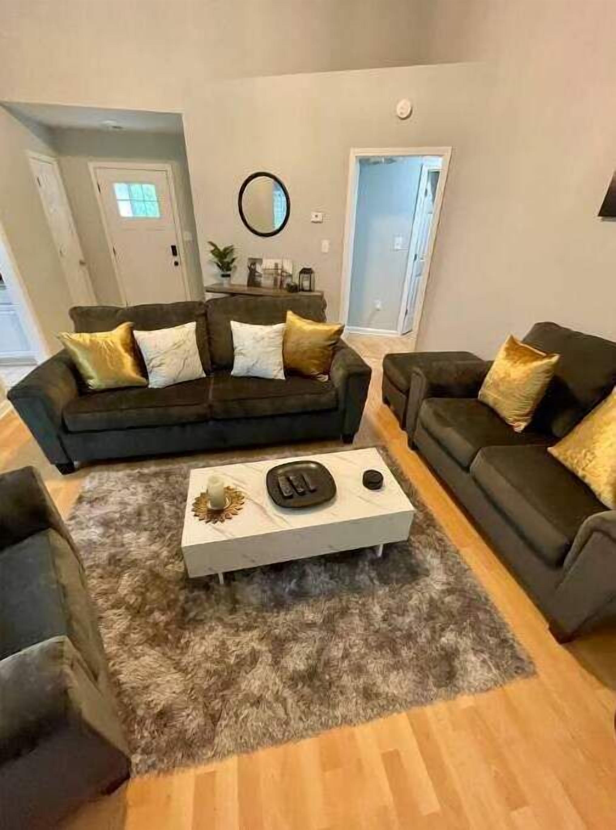 A living room with two dark sofas, a white coffee table, and a shaggy rug.