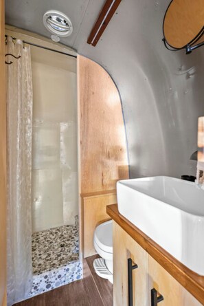 A compact bathroom with a shower, toilet, and sink. - Airstream - (Buckeye) (Dunsmuir)