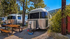 Un véhicule récréatif (VR) de la marque « AIRSTREAM » est stationné dans un terrain de camping.