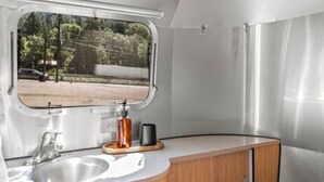 Une cuisine compacte pour camping-car, dotée d’une fenêtre, d’un évier et de placards en bois.
