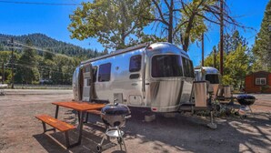 Un camping-car à l’arrêt, équipé d’une table de pique-nique et d’un barbecue, situé dans un terrain de camping.