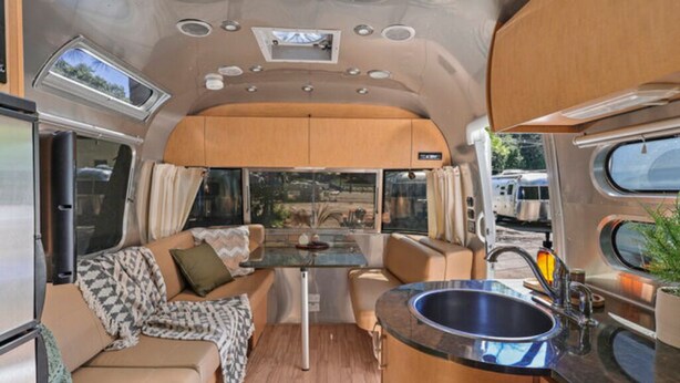 Een compact interieur van een camper met een kitchenette, zithoek en een klein eettafeltje.
