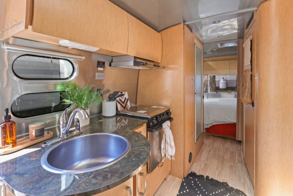 A compact kitchen with a sink, stove, and cabinets.