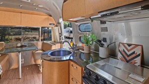 Een compacte camperkeuken met een spoelbak, fornuis en een klein zitgedeelte.