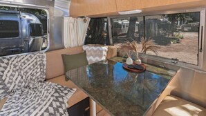 Een gezellig interieur van een camper met een eettafel, beklede zitplaatsen en uitzicht op de omgeving.