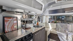 Et moderne camper køkken med kogeplade, vask og siddeplads.