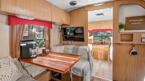 Een compact camperinterieur met een kitchenette, zithoek en een televisie.