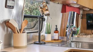 Een keuken met houten keukengerei, een plant, een fles en een spoelbak.