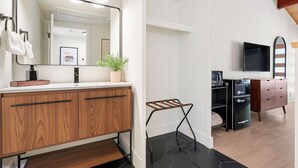 Un baño moderno con tocador de madera, un espejo grande y televisor integrado.