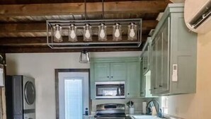 A kitchen with a central island, wooden flooring, and bar stools. - Enzo's Bungalow (Russellville)