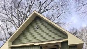 A small, single-story house with a green roof and brick foundation. - Enzo's Bungalow (Russellville)