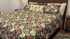 Un llit amb un edredó floral, un capçal i un quadre de paisatge urbà a sobre.