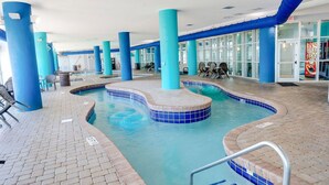 An indoor swimming pool with blue-tiled edges, surrounded by blue pillars, and a tiled floor. - Oceanfront, 3 bedrooms & 3 bathrooms, sleeps 10 (Myrtle Beach)