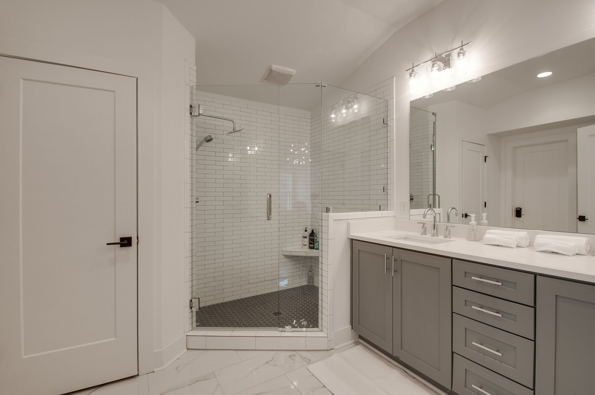 A modern bathroom with a walk-in shower, a large mirror, and a vanity with a sink and towel rack.