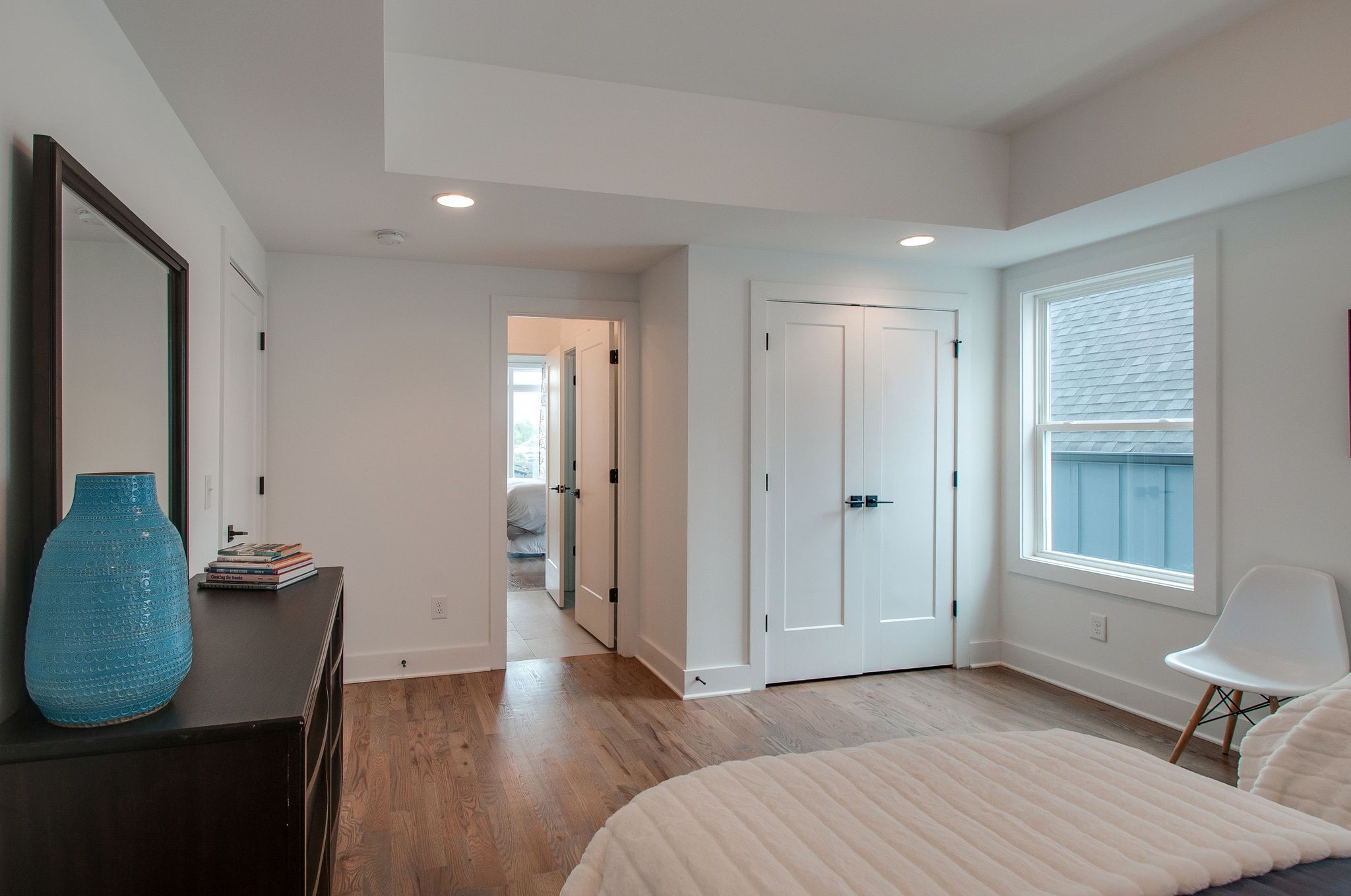 Une chambre à coucher avec un lit, une commode, un miroir et une fenêtre.