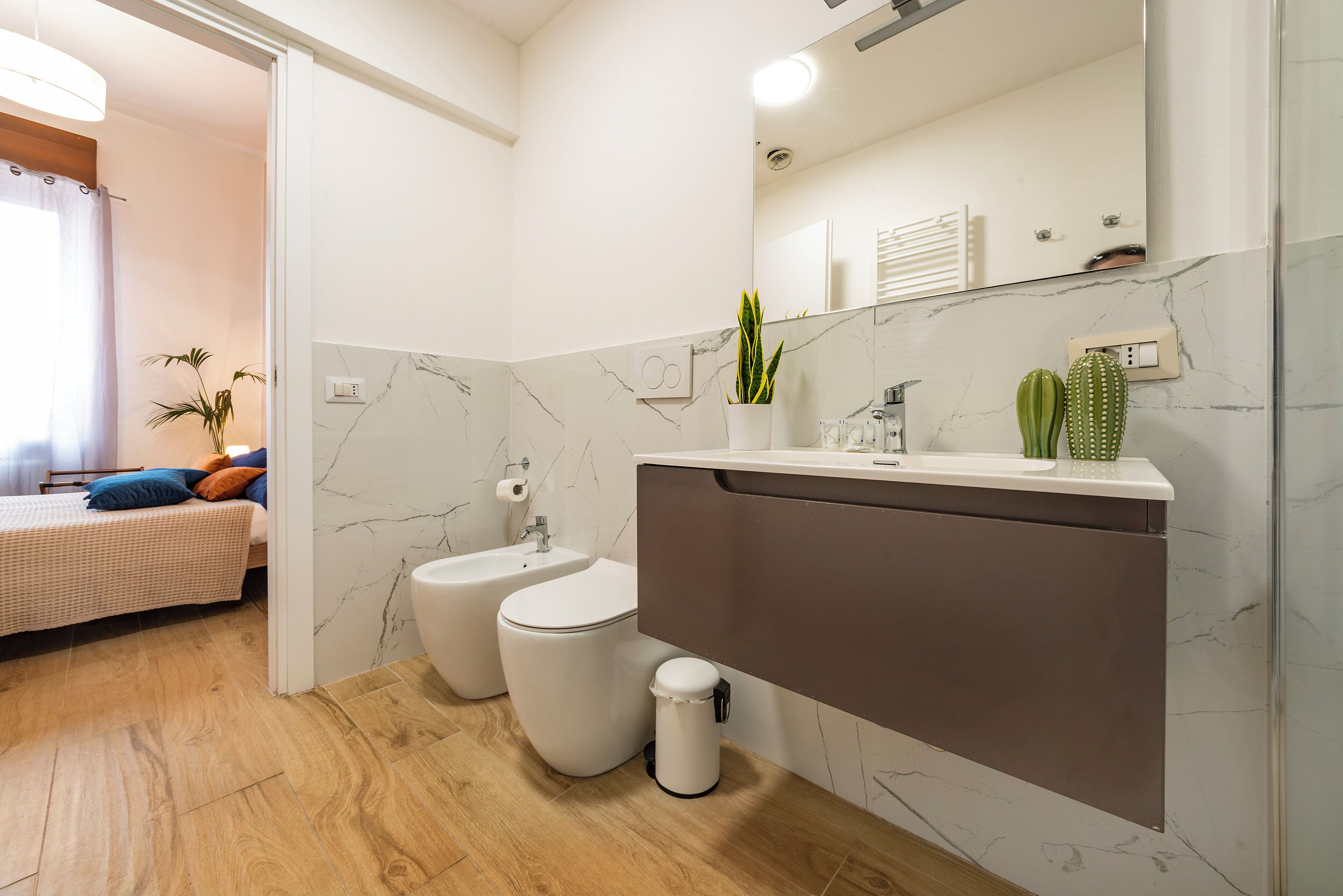 Une salle de bain moderne avec un pare-baignoire en marbre, un lavabo blanc et un bidet.
