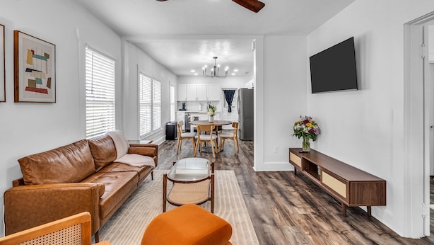 A modern living room with a leather sofa, a glass coffee table, and a wooden console table.