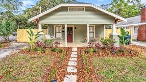 A single-story house with a porch, a front yard with a stone pathway, and a wooden fence.