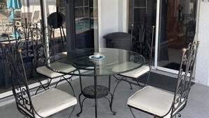 A glass-top table with four chairs, a ceiling fan, and a view of a swimming pool through glass doors. - Rare & Amazing 3 bdrm 2 bath apt with pool gives you a home away from home feel. (Lutz)