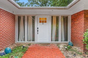 A house with a white door, a brick exterior, and a covered porch with curtains. - Cozy Guest House Apartment (Greensboro)