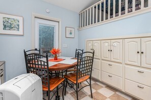 A dining area with a round table, four chairs, and a vase with flowers. - Cozy Guest House Apartment (Greensboro)