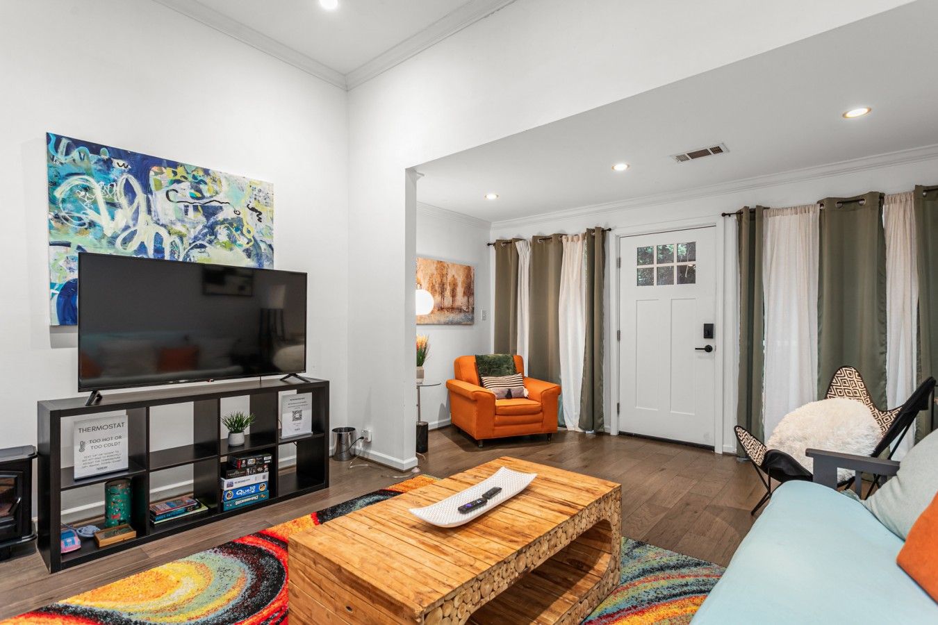 A modern living room with a flat-screen TV, a wooden coffee table, and a colorful rug.