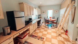 A compact kitchen with a refrigerator, stove, and dining area with chairs and a table.