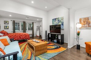 A modern living room with a bed, a TV, a coffee table, and a colorful rug. - Cozy Guest House Apartment (Greensboro)