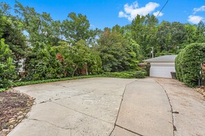 A residential driveway leading to a garage, surrounded by dense foliage and trees. - Cozy Guest House Apartment (Greensboro)