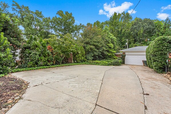 A residential driveway leading to a garage, surrounded by dense foliage and trees. - Cozy Guest House Apartment (Greensboro)