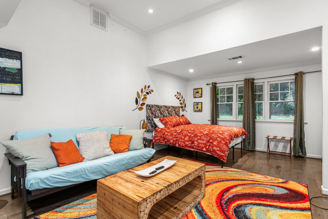 A modern bedroom with a sofa, a bed, and a wooden coffee table.