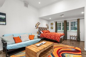 A modern bedroom with a sofa, a bed, and a wooden coffee table. - Cozy Guest House Apartment (Greensboro)