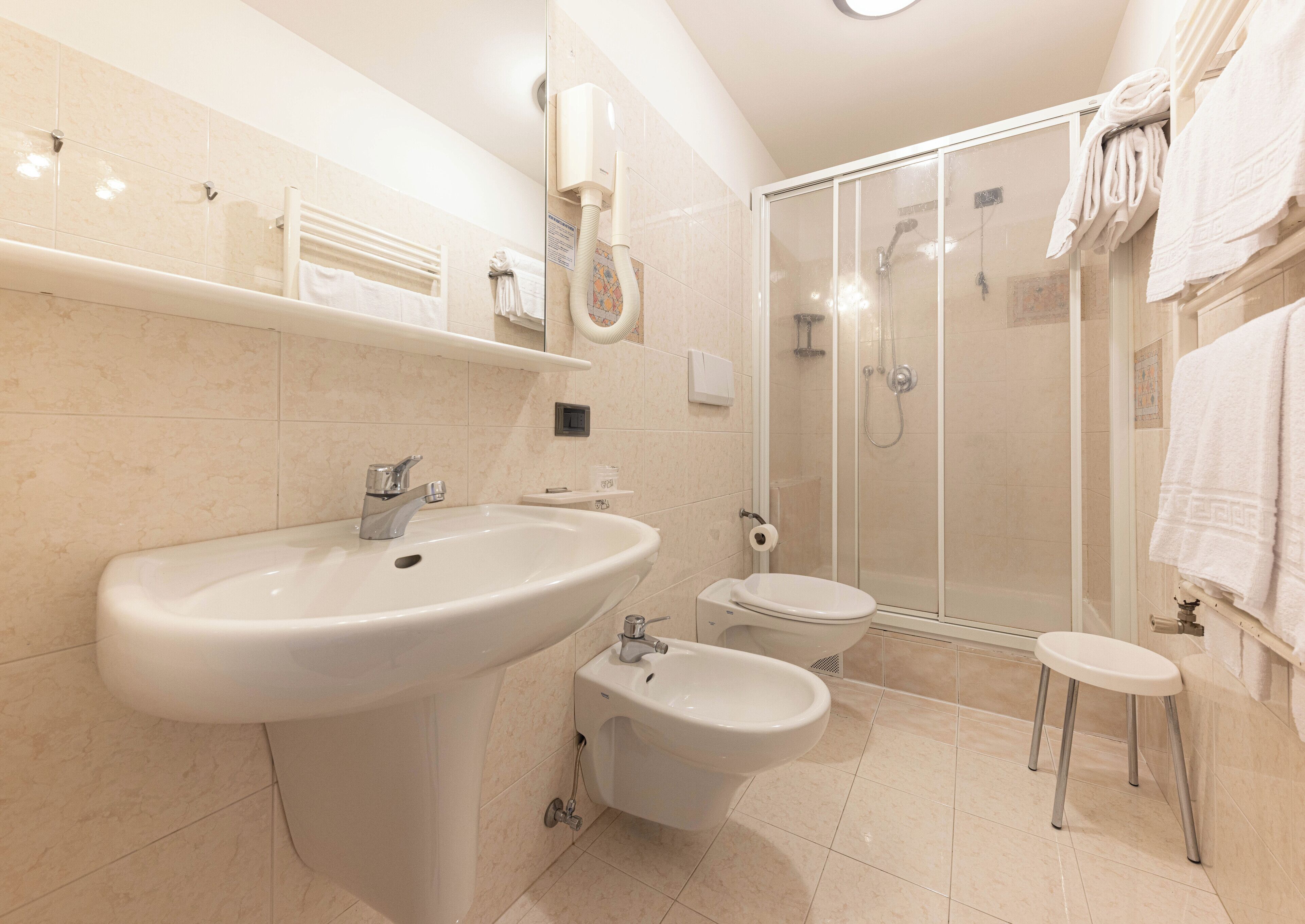 Une salle de bain moderne dotée d’un grand lavabo, d’un bidet, de toilettes et d’une douche à parois de verre.