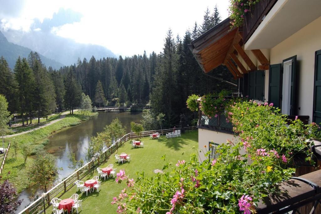 A balcony with a view of a river, surrounded by greenery and trees.