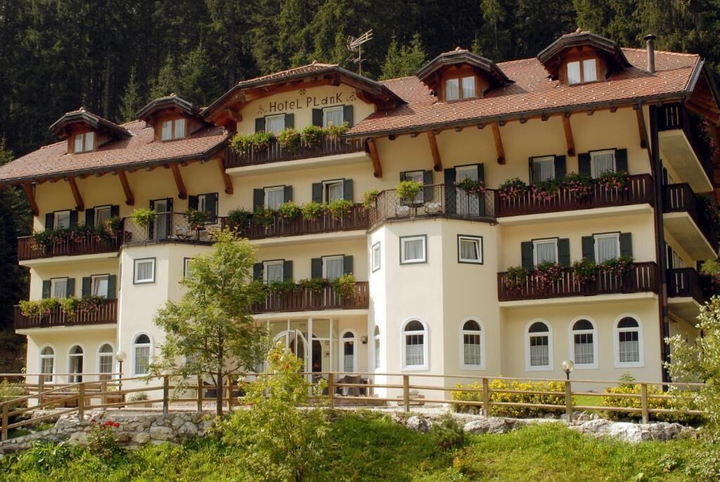 Un hotel de varios pisos con balcones, fachada de piedra y un letrero que dice "Hotel Plank".