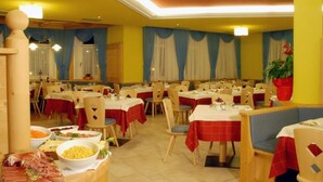Un espace repas comprenant plusieurs tables et chaises, dont certaines sont recouvertes de nappes rouges.