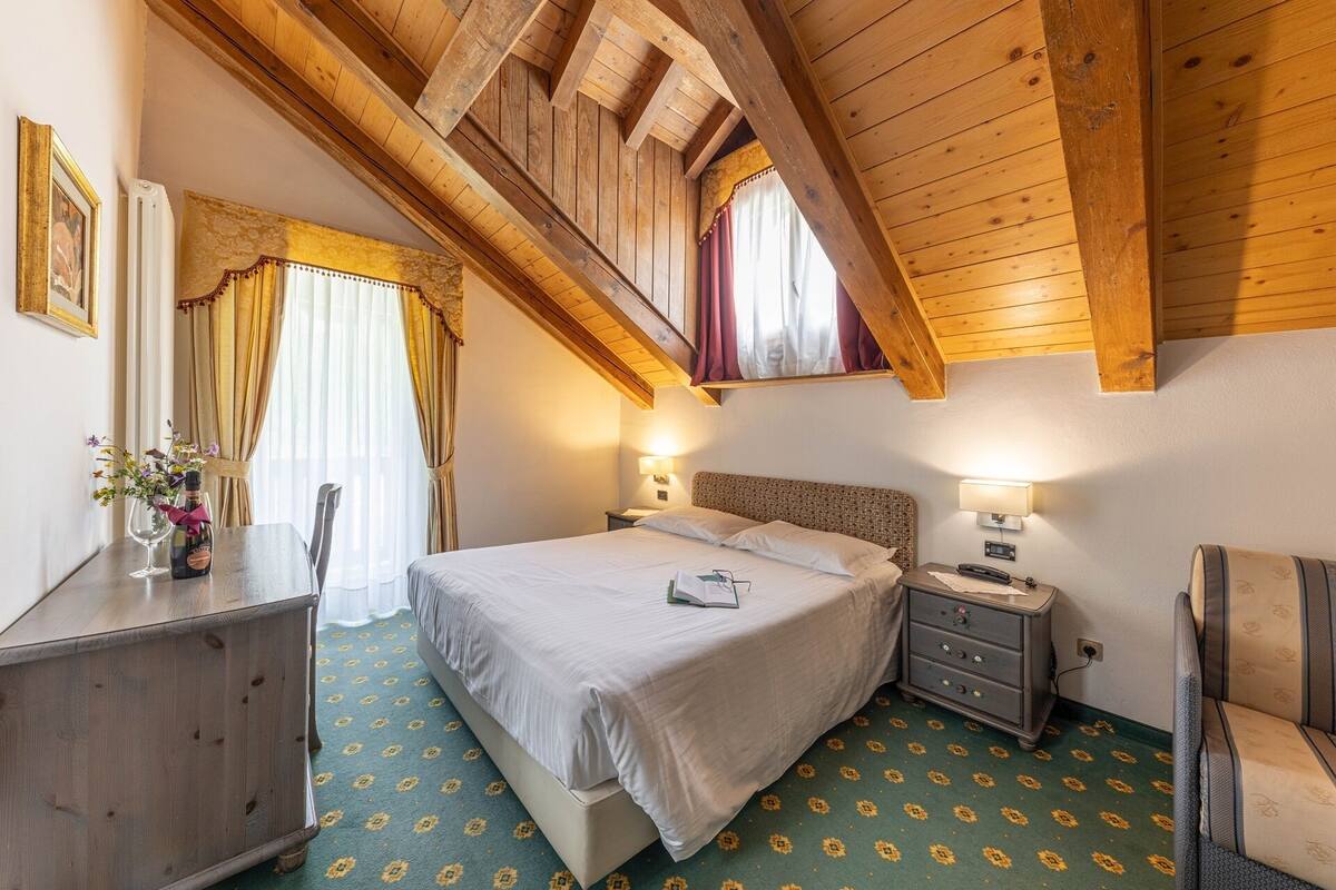A bedroom with a bed, bedside tables, a dresser, and a window with curtains.